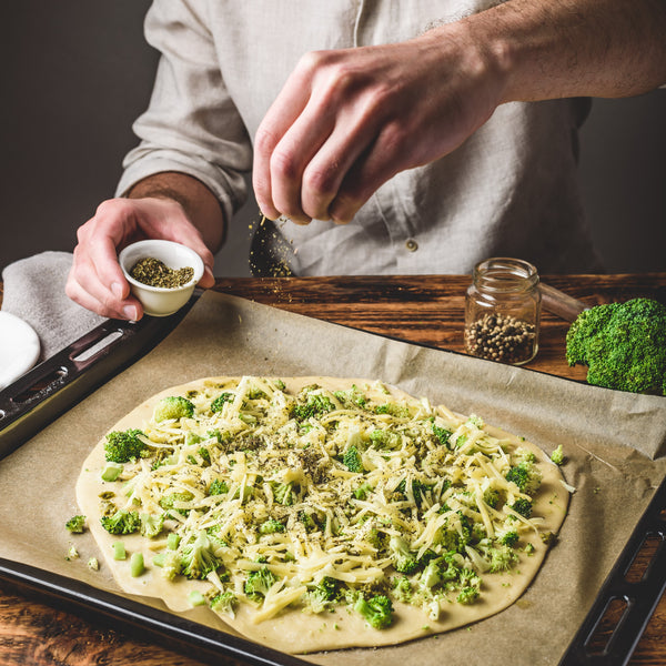 man-cooks-pizza-with-broccoli-and-pesto-sauce